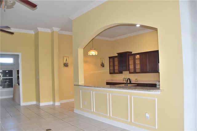 kitchen with light tile patterned floors, glass insert cabinets, crown molding, dark brown cabinets, and a sink