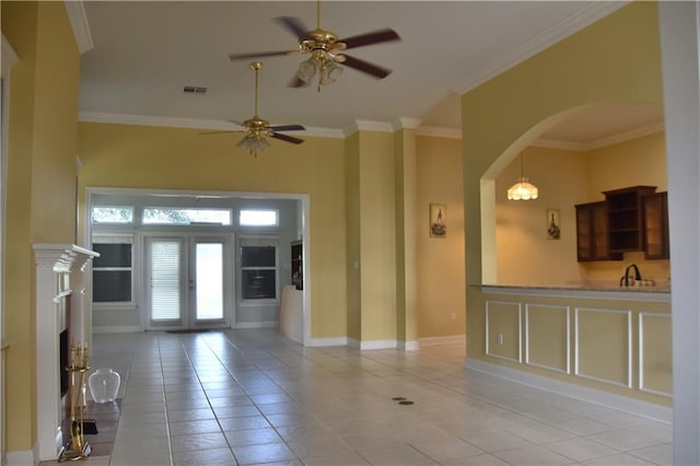 unfurnished living room featuring light tile patterned floors, visible vents, arched walkways, crown molding, and french doors