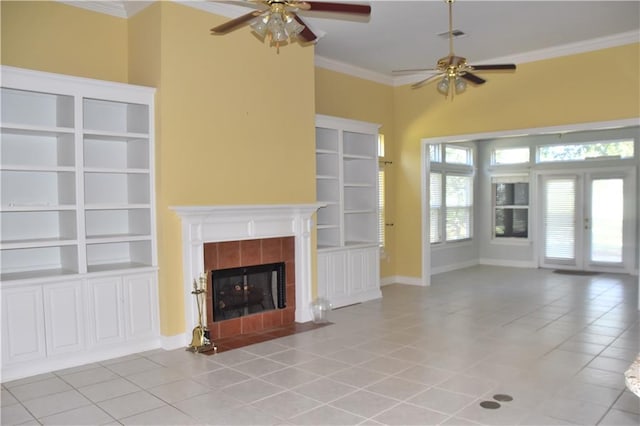 unfurnished living room featuring french doors, crown molding, light tile patterned floors, ceiling fan, and a tile fireplace