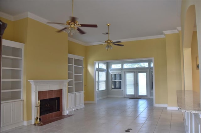 unfurnished living room featuring french doors, ornamental molding, a tiled fireplace, and baseboards