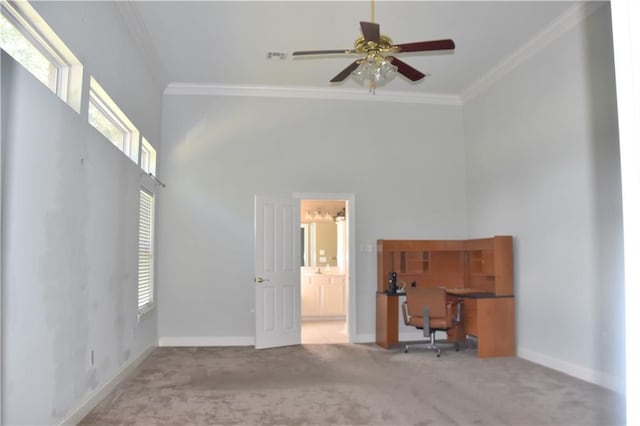 carpeted empty room featuring baseboards, a high ceiling, ornamental molding, and a ceiling fan