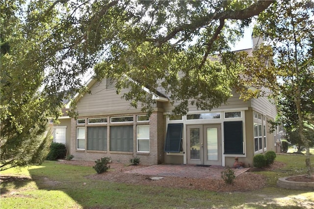 view of front of house featuring a patio area, french doors, brick siding, and a front yard