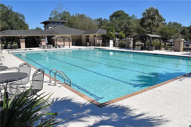 community pool with a patio area and fence