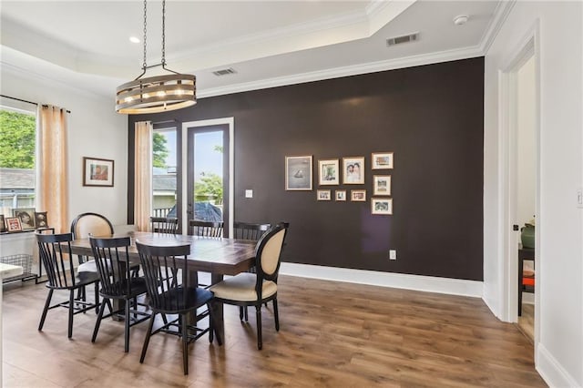 dining room with a wealth of natural light, dark hardwood / wood-style floors, crown molding, and an inviting chandelier