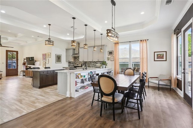 dining area featuring wood-type flooring, a healthy amount of sunlight, and crown molding