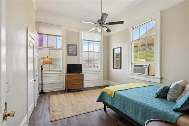 bedroom with dark wood-type flooring, ceiling fan, multiple windows, and crown molding