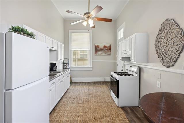 kitchen with dark hardwood / wood-style flooring, white appliances, a healthy amount of sunlight, and white cabinets