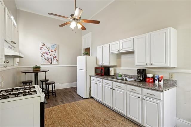 kitchen featuring dark hardwood / wood-style flooring, sink, white cabinets, custom exhaust hood, and white appliances