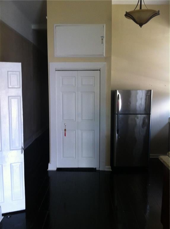 kitchen with stainless steel refrigerator, white cabinetry, and pendant lighting