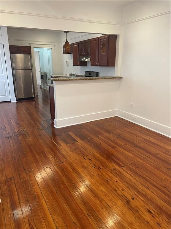 kitchen with stainless steel fridge, dark brown cabinetry, pendant lighting, dark wood-type flooring, and kitchen peninsula