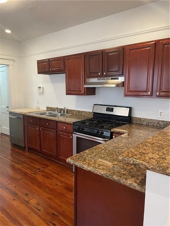 kitchen with stainless steel appliances, dark stone countertops, sink, and dark hardwood / wood-style flooring