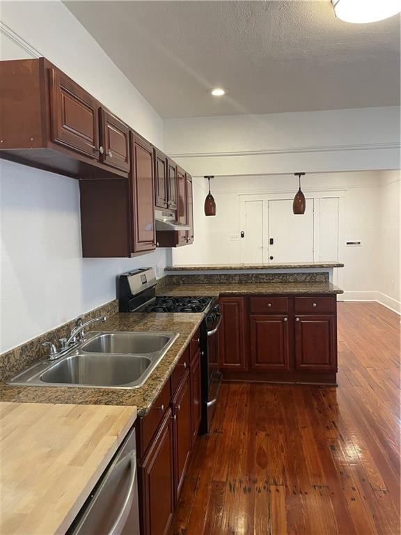 kitchen with a textured ceiling, sink, stainless steel gas range oven, dark hardwood / wood-style floors, and wood counters