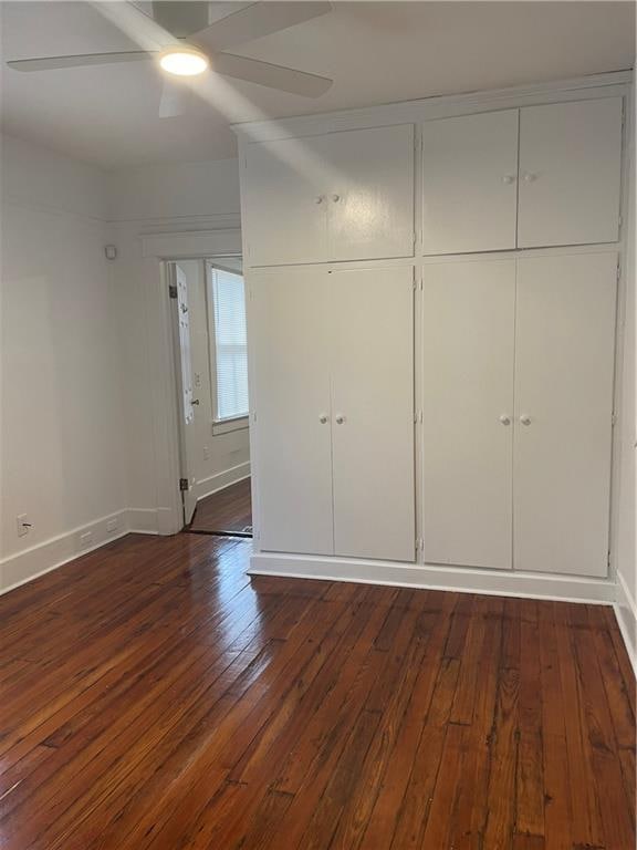 unfurnished bedroom featuring ceiling fan and dark hardwood / wood-style flooring