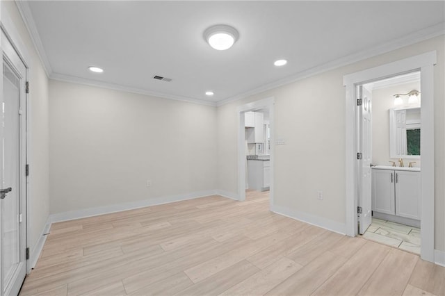 empty room with sink, light hardwood / wood-style flooring, and ornamental molding