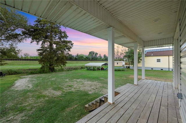 deck at dusk featuring a yard