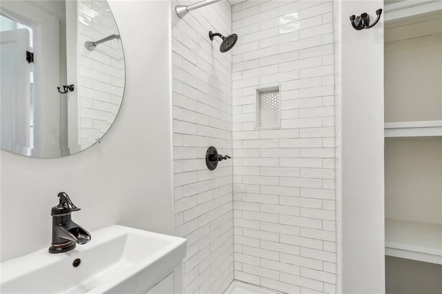 bathroom featuring tiled shower and sink