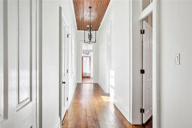 hallway with wood-type flooring, wooden ceiling, and a notable chandelier