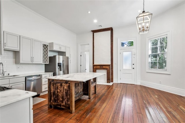 kitchen featuring dark hardwood / wood-style flooring, a center island, decorative backsplash, hanging light fixtures, and appliances with stainless steel finishes