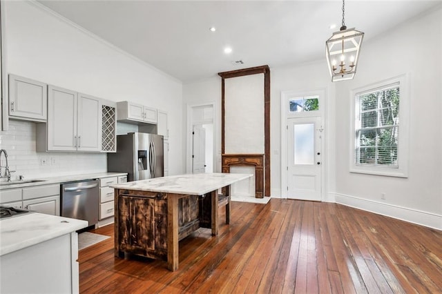 2927 Palmyra St, New Orleans, LA 70119 - kitchen with appliances with stainless steel finishes, a sink, backsplash, dark wood-style floors, and a chandelier