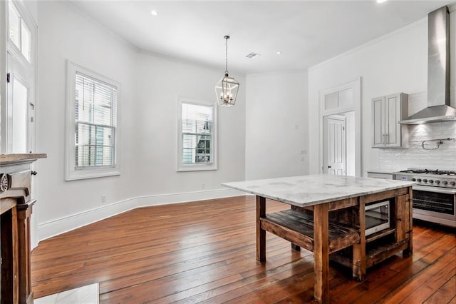 2927 Palmyra St, New Orleans, LA 70119 - kitchen with wall chimney range hood, stainless steel appliances, dark wood finished floors, a chandelier, and decorative backsplash