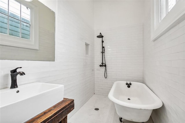 bathroom featuring a tub to relax in, tile walls, and sink