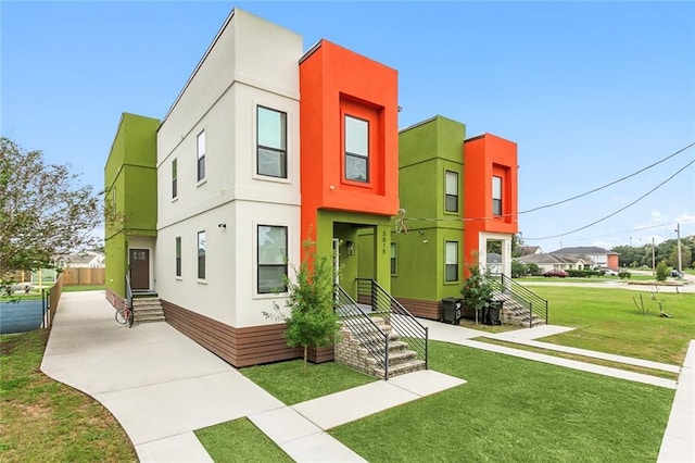 view of front of property featuring entry steps, a front yard, and stucco siding