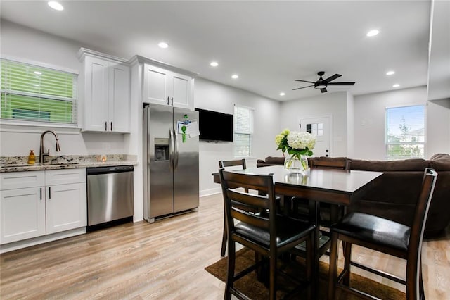 kitchen featuring light stone countertops, recessed lighting, light wood-style floors, stainless steel appliances, and a sink