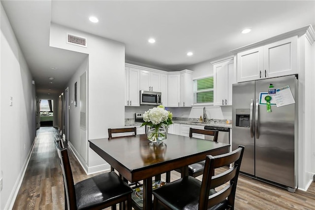 kitchen featuring white cabinetry, a wealth of natural light, stainless steel appliances, and light wood-type flooring