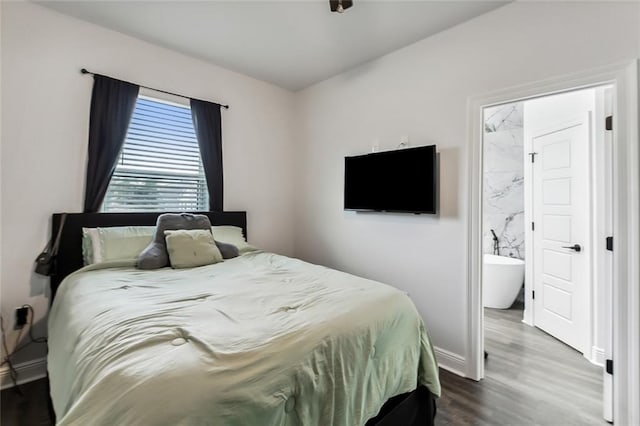 bedroom featuring ensuite bath and dark hardwood / wood-style flooring