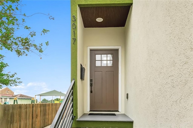 property entrance with fence and stucco siding