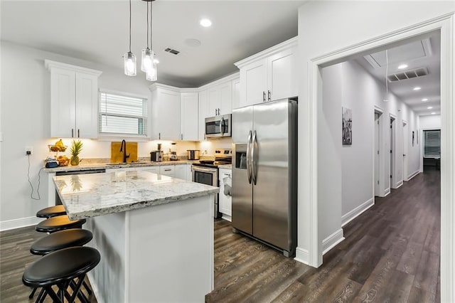 kitchen with white cabinetry, appliances with stainless steel finishes, a center island, and dark hardwood / wood-style flooring