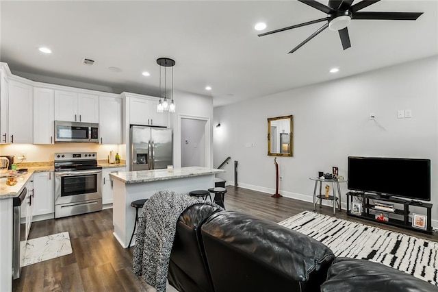 kitchen featuring stainless steel appliances, light stone countertops, white cabinets, and decorative light fixtures