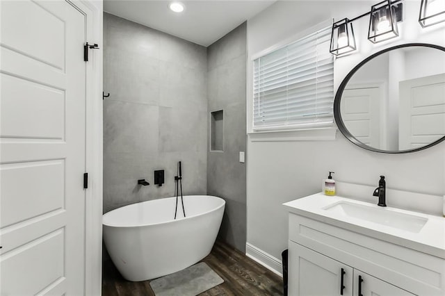 bathroom with hardwood / wood-style floors, vanity, and a tub