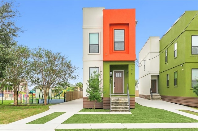 view of front of property featuring stucco siding, entry steps, and a front lawn