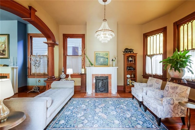 living area with wood-type flooring, ornate columns, and a notable chandelier