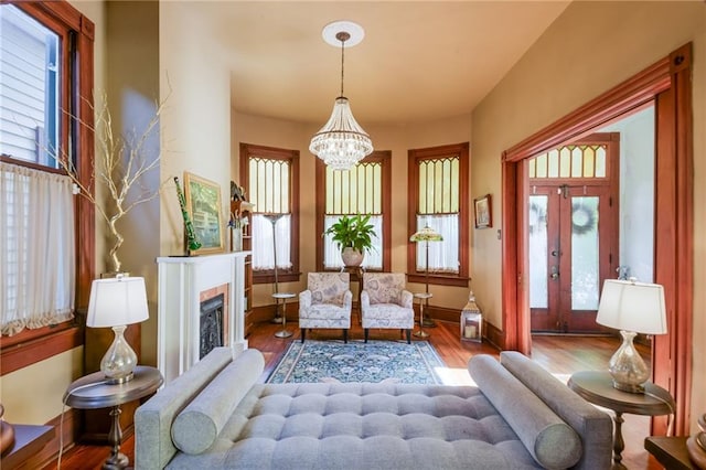 living area with an inviting chandelier, hardwood / wood-style floors, a healthy amount of sunlight, and french doors