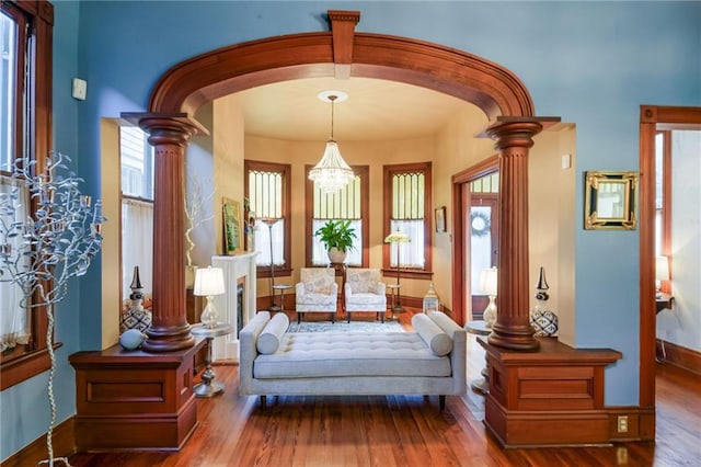 living area featuring an inviting chandelier, hardwood / wood-style flooring, and ornate columns