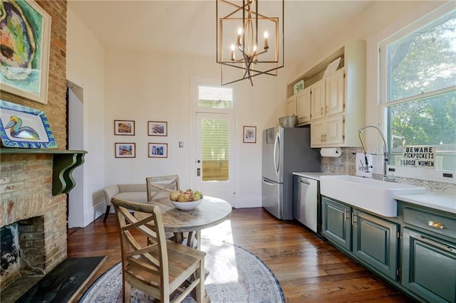 kitchen featuring stainless steel appliances, sink, a fireplace, dark wood-type flooring, and decorative backsplash