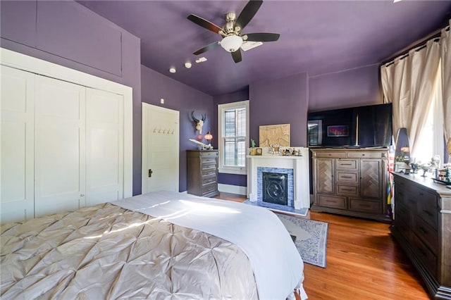 bedroom with light wood-type flooring, ceiling fan, and a closet