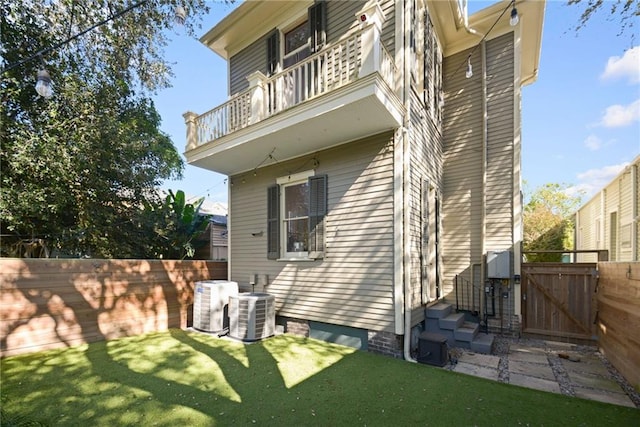 exterior space featuring central air condition unit, a balcony, and a yard