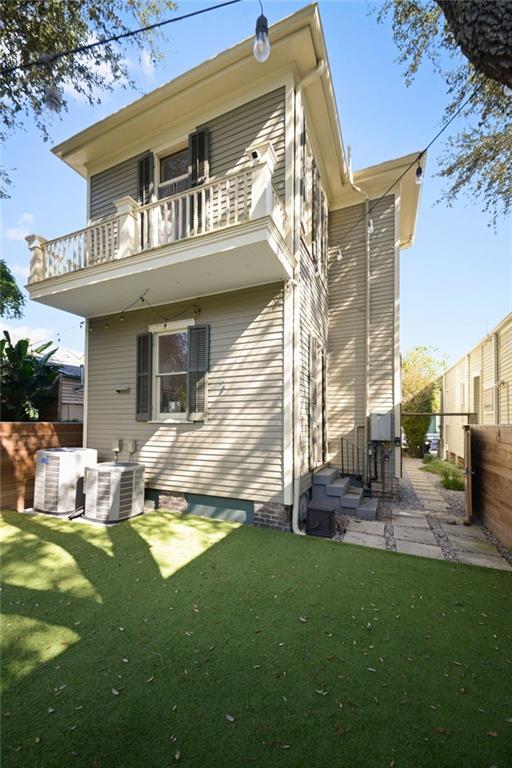 rear view of house featuring a lawn, a balcony, central AC, and a patio area