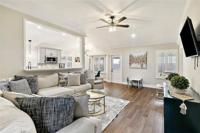 living room featuring dark wood-type flooring, a wealth of natural light, ceiling fan, and crown molding