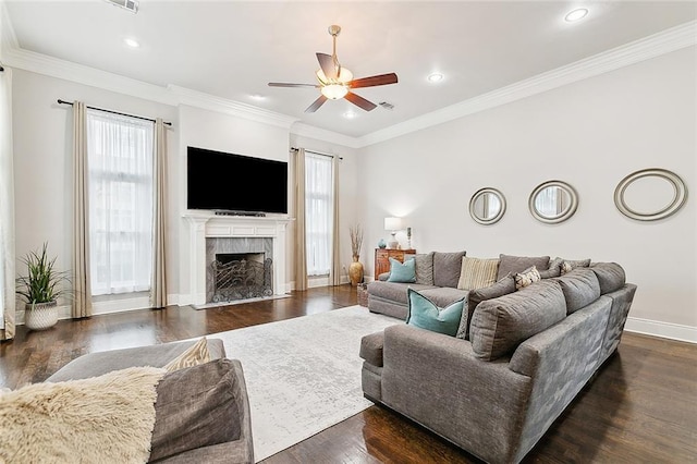 living room with dark wood-type flooring, a high end fireplace, plenty of natural light, and crown molding