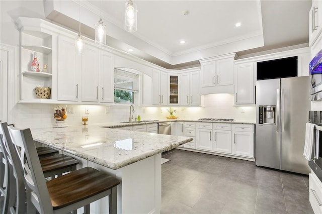 kitchen with stainless steel appliances, pendant lighting, a breakfast bar, white cabinets, and kitchen peninsula