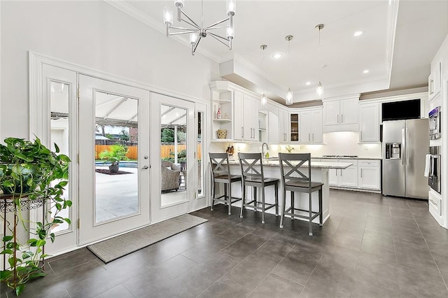 kitchen with white cabinets, french doors, stainless steel appliances, and hanging light fixtures