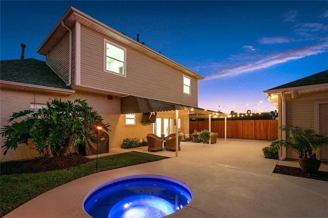 back house at dusk featuring an outdoor hot tub, a patio area, and an outdoor hangout area