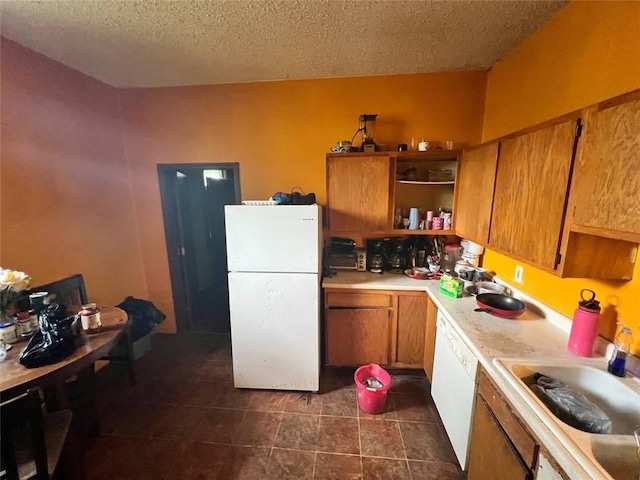 kitchen featuring a textured ceiling, white appliances, and sink