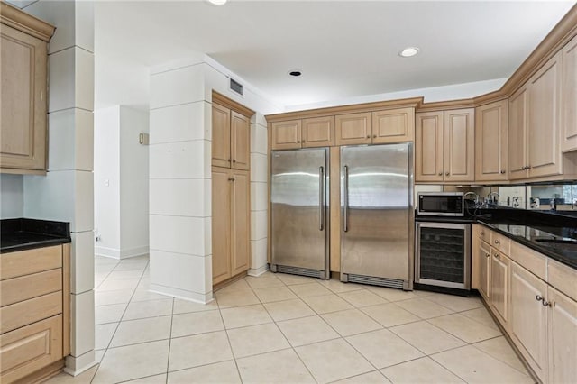 kitchen with light tile patterned floors, stainless steel appliances, wine cooler, and dark stone counters