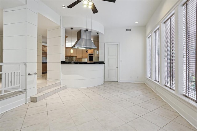 kitchen featuring stainless steel oven, exhaust hood, ceiling fan, light tile patterned floors, and decorative light fixtures