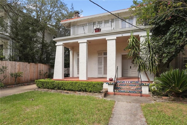 view of front of property featuring a balcony, covered porch, and a front yard